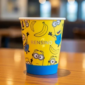 Gobelet en papier jaune avec personnages de dessin animé et bananes, adapté pour l'emballage de boissons ou de vente au détail, design personnalisable