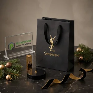 Sac en papier noir avec logo imprimé en or et décoration en ruban, adapté à l'emballage cadeau ou de détail, impression de logo personnalisée disponible