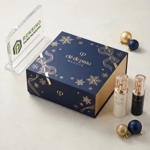Caja rígida de papel azul y dorado Clé de Peau Beauté con patrón de copo de nieve y cinta, adecuada para empaques cosméticos o de regalo, servicio OEM/ODM disponible