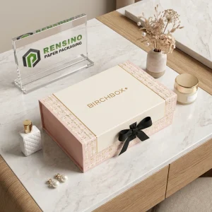 Boîte cadeau en papier rose et blanc avec ruban noir et texte imprimé “BIRCHBOX”, adaptée pour un emballage cadeau, de vente au détail ou cosmétique, design personnalisé disponible