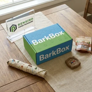 Boîte cadeau en papier bleue et verte avec texte imprimé “BarkBox” et motif d'arbre, adaptée pour les cadeaux, le commerce de détail ou l'emballage alimentaire, conception personnalisée disponible