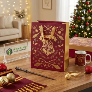 Bolsa de papel burdeos y dorado con el escudo de Hogwarts y patrón de elementos mágicos, adecuada para embalaje de regalos o venta al por menor, impresión de logo personalizada disponible